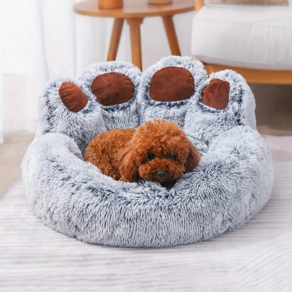 Fluffy paw-shaped pet bed with a small dog inside, placed on a light-colored surface.