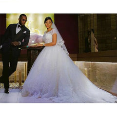 Man in a suit and woman in a white wedding dress standing together indoors.
