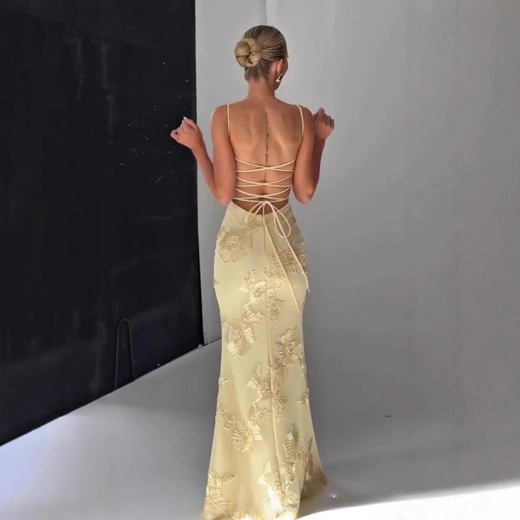 Woman wearing a gold evening gown with floral embroidery in a studio setting.