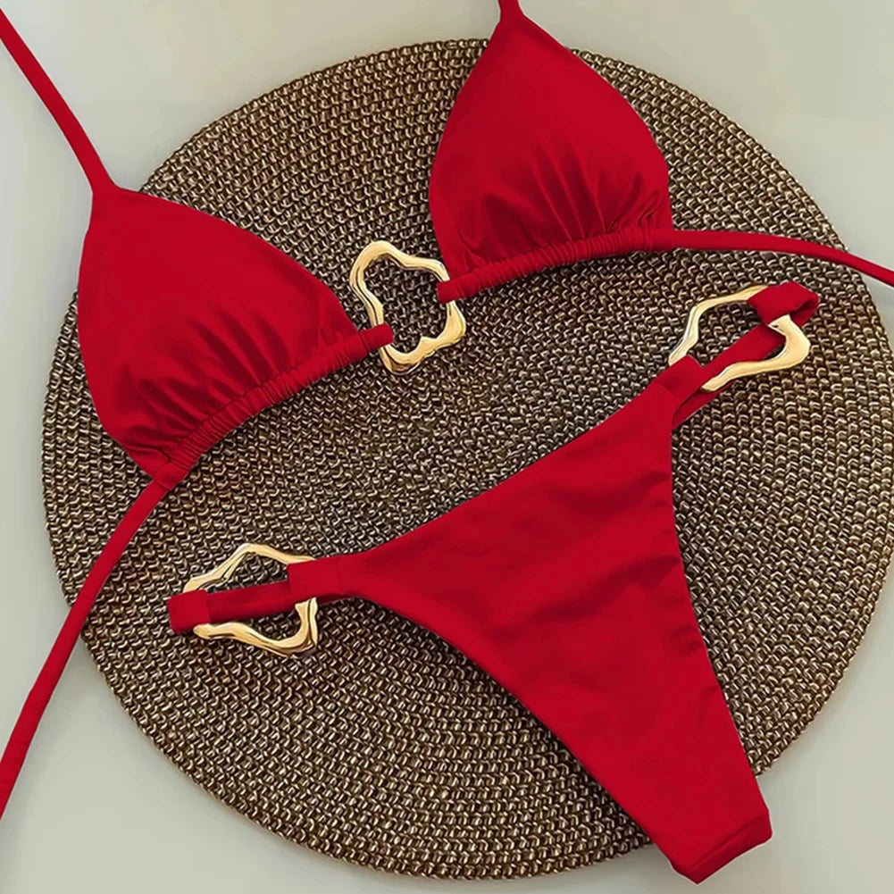 Red bikini set with gold hardware on a textured surface