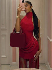 Woman in a red dress holding a red handbag in front of a mirror.