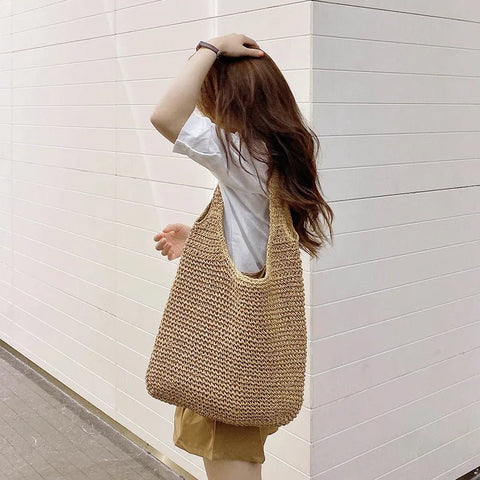 Person holding a woven bag against a white wall