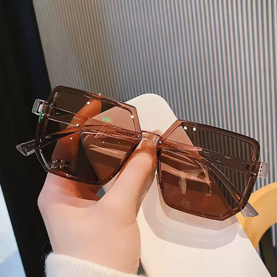 Brown sunglasses held by a hand with a blurred background