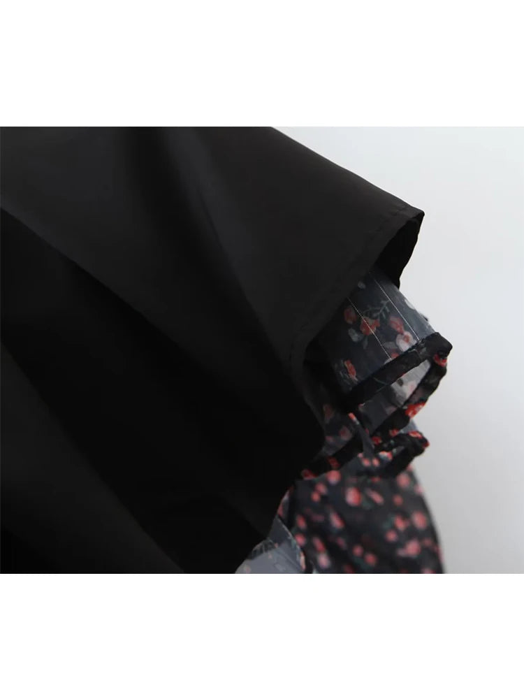 Black fabric draped over a patterned fabric with red and black design on a white background