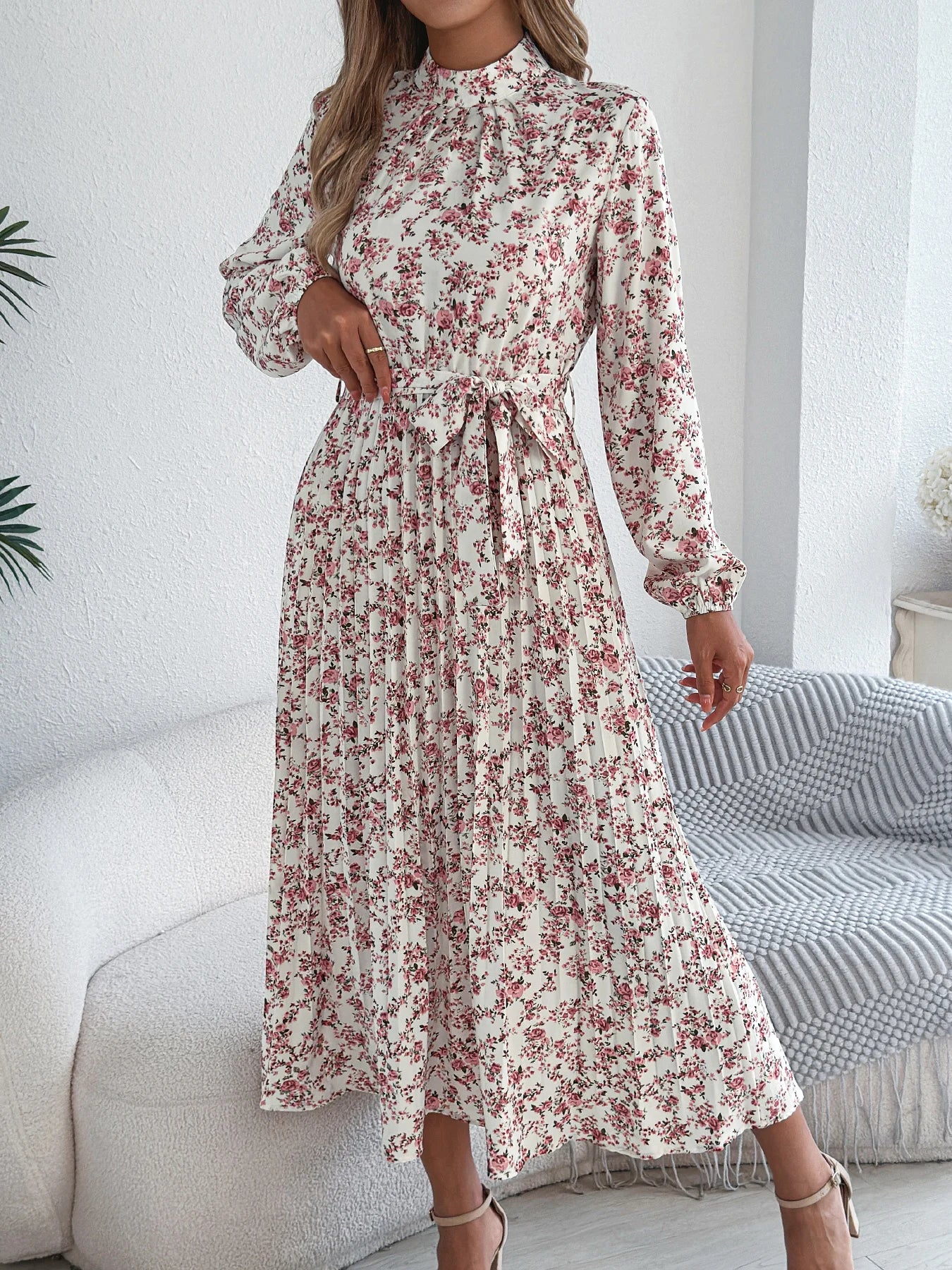 Woman wearing a floral dress in a minimalistic room.