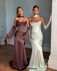 Two women in elegant evening gowns standing side by side indoors.