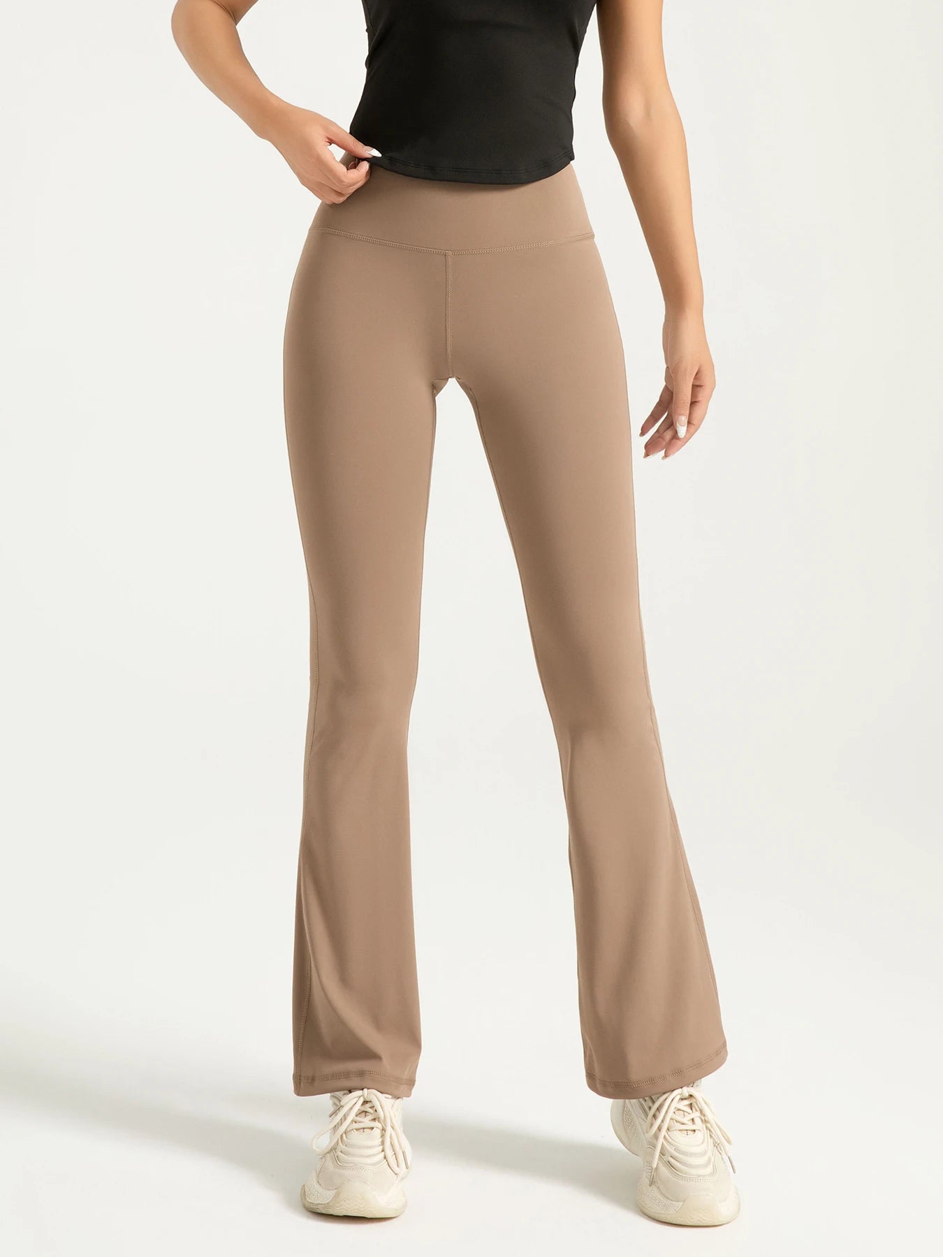 Beige flared pants worn by a person on a white background