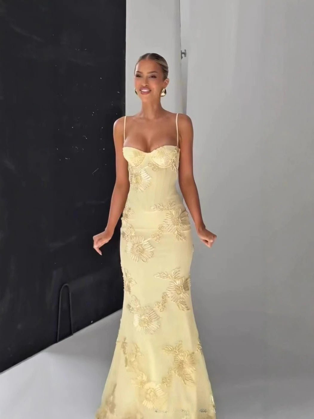 Woman wearing a yellow lace evening gown against a neutral background