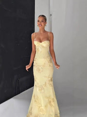 Woman wearing a yellow lace evening gown against a neutral background