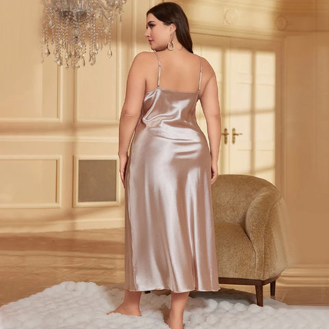 Woman in a satin nightgown standing in a luxurious room with a chandelier.
