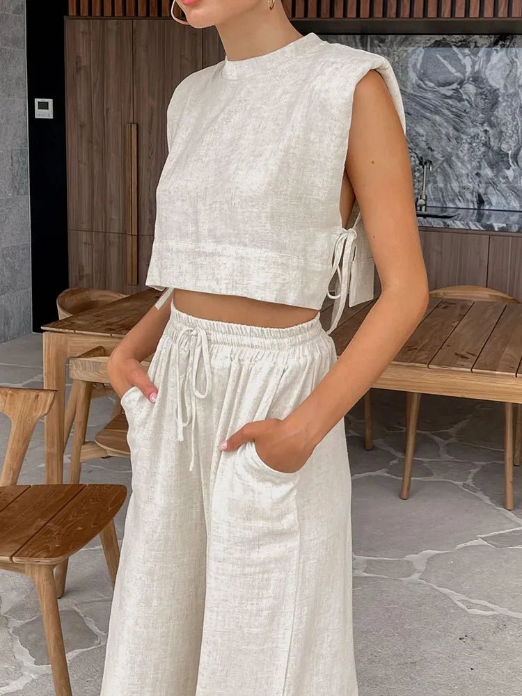 Person wearing a white sleeveless top and wide-leg pants in an indoor setting.
