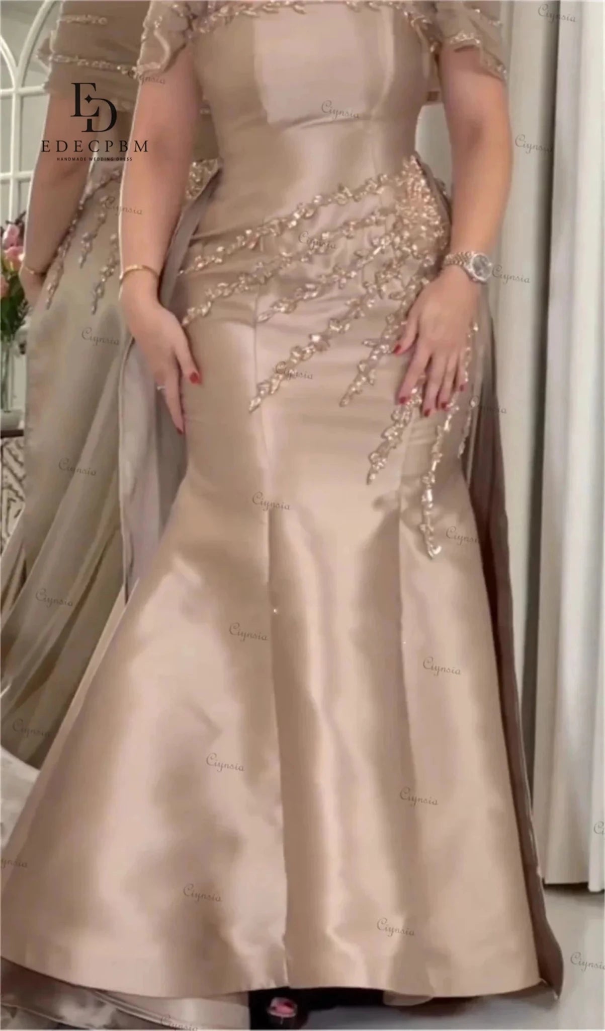 Beige evening gown with intricate beadwork on a neutral background