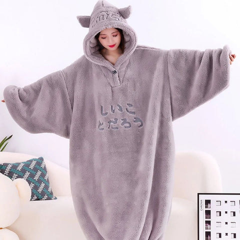 Person wearing a gray fleece onesie with cat ears on a white background