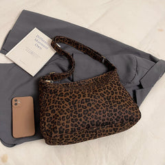 Leopard print handbag with a phone and book on a gray fabric background