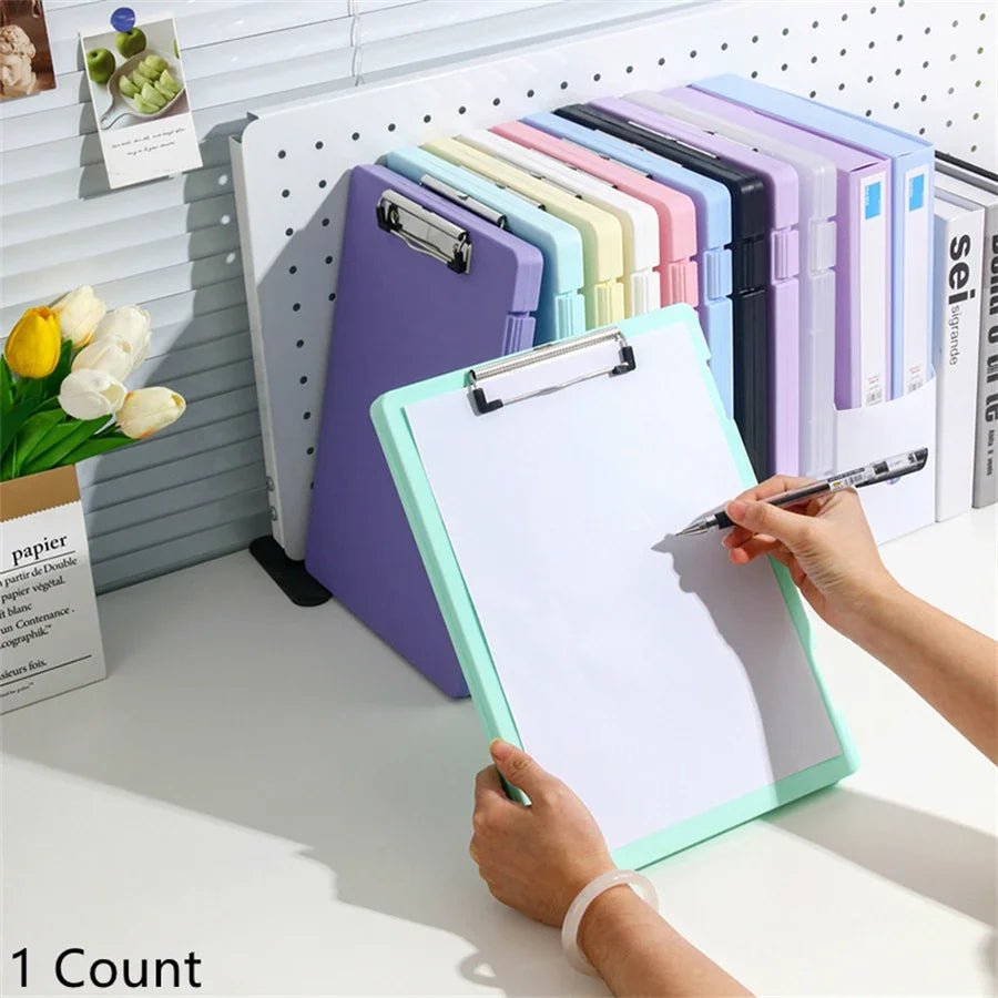 Person using a green clipboard with a pen, surrounded by colorful clipboards on a pegboard.