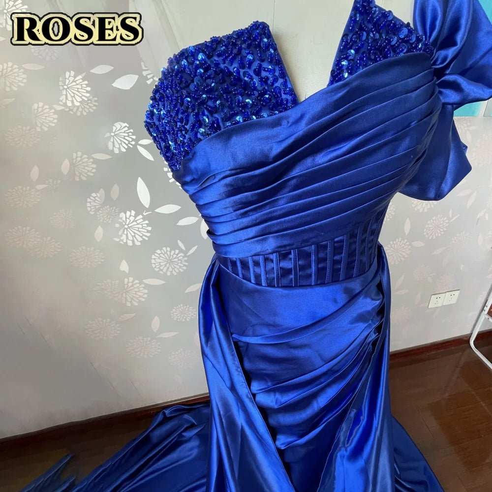 Blue evening gown with sequin details on a floral patterned wall.