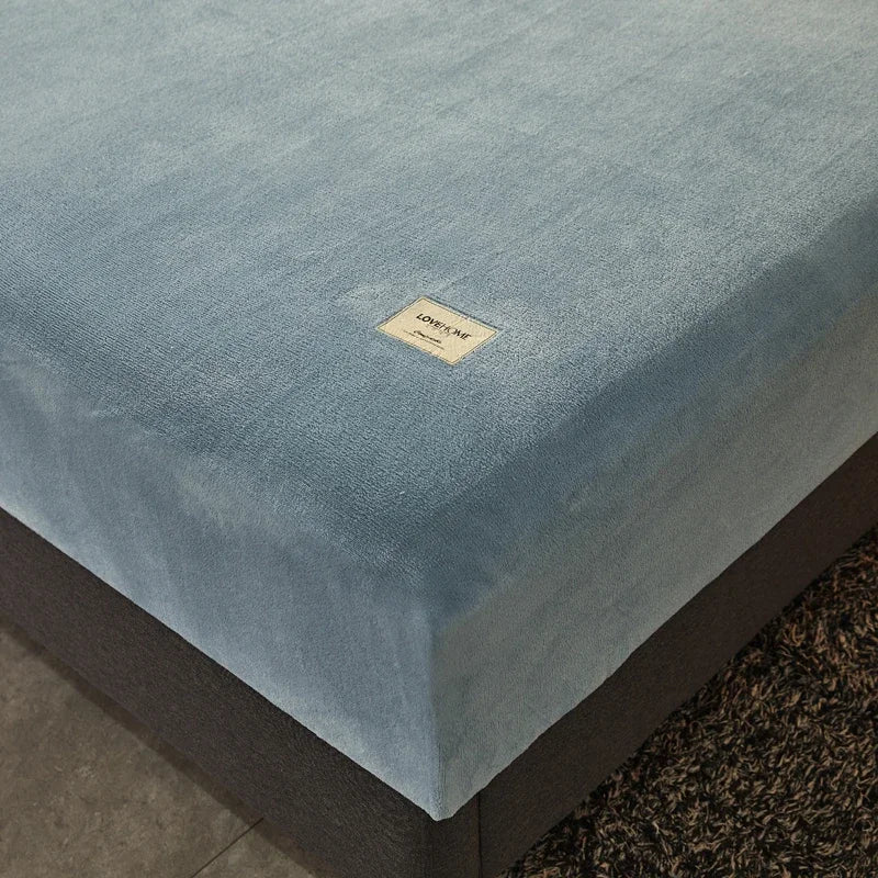 Blue mattress cover with a brand logo on a bed corner.