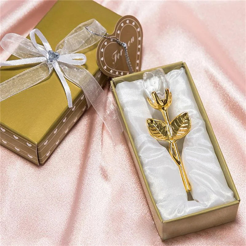 Gold rose-shaped object in a box with a bow on a pink fabric background