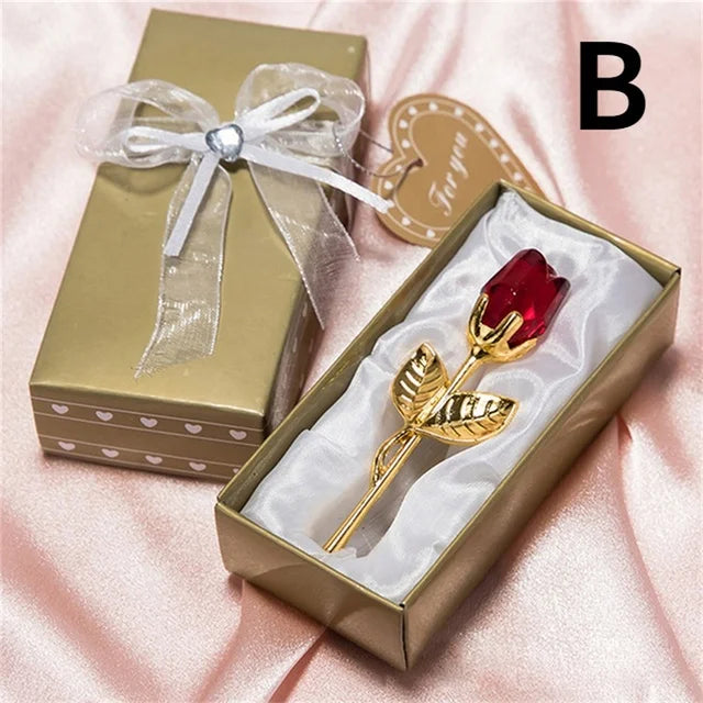 Gold rose with red gemstone in a decorative box on a pink background
