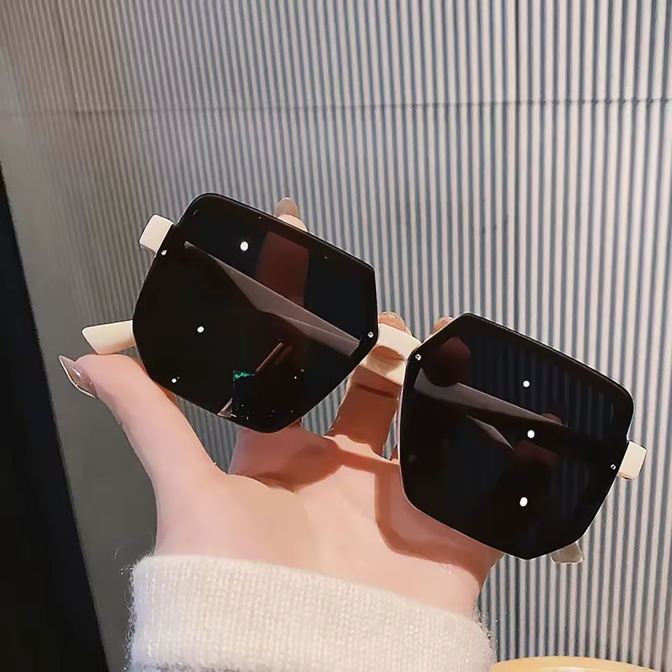 Black sunglasses held by a hand against a striped background
