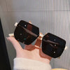 Black sunglasses held by a hand against a striped background