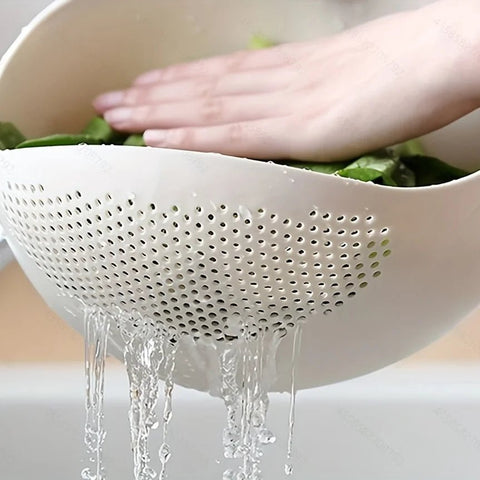 Person washing green vegetables in a white colander over a sink.