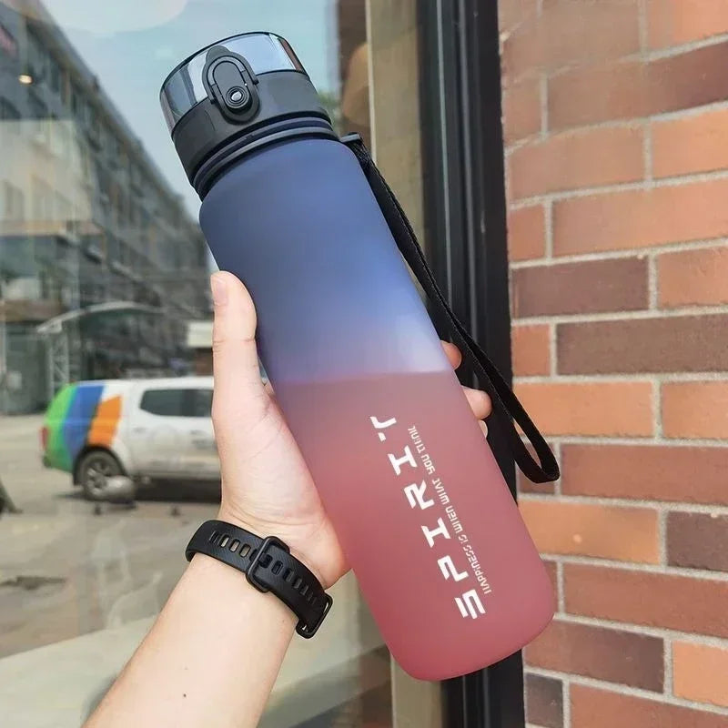 Gradient water bottle held by a person with a brick wall and street in the background