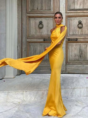 Woman in a yellow evening gown standing in front of a wooden door.