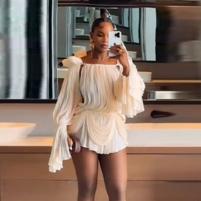 Person taking a mirror selfie wearing a white off-shoulder outfit in a kitchen.