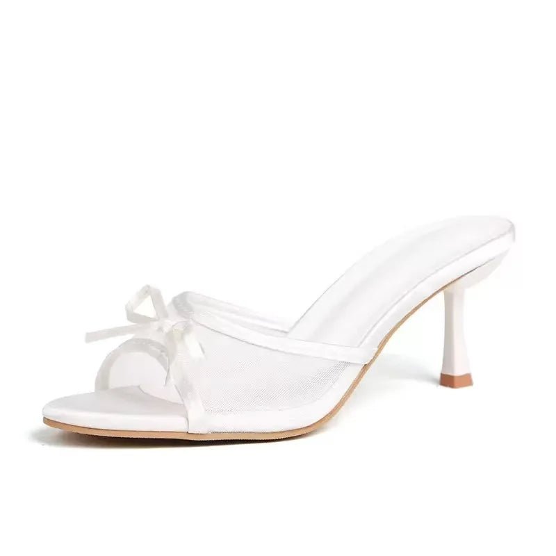 White high-heeled shoe with a bow on a white background