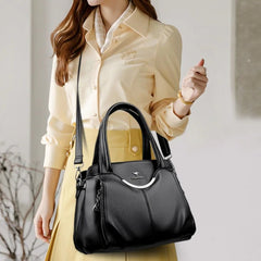 Woman holding a black handbag against a neutral background