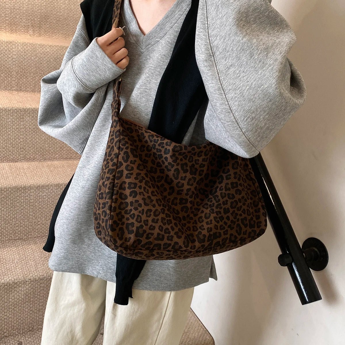 Person holding a leopard print bag with a neutral background