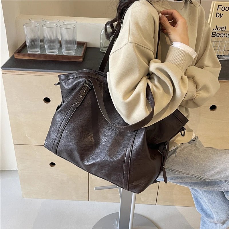 Person holding a brown leather bag in a casual setting
