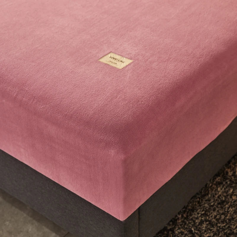 Pink mattress cover with a brand label on a bed