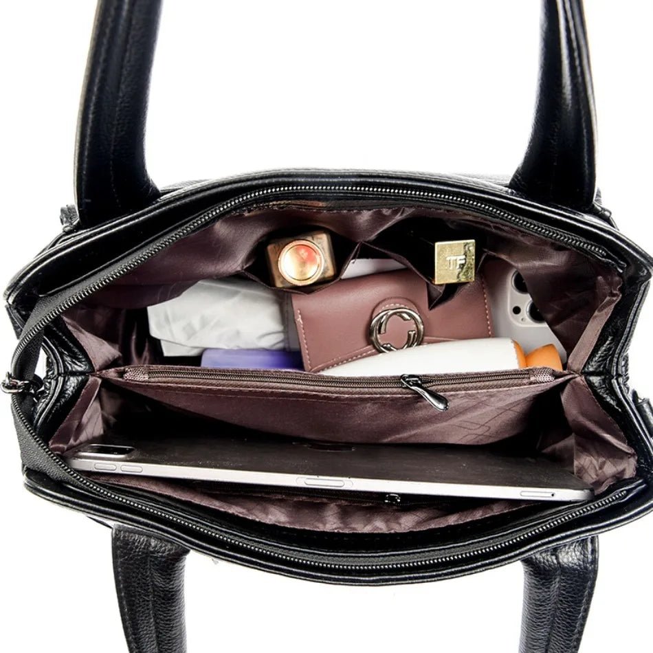 Black handbag with its interior open, revealing various items including a phone and a wallet.