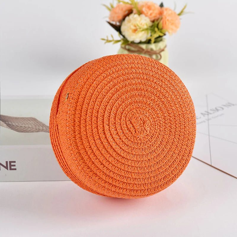Round orange woven mat on a light surface with flowers in the background