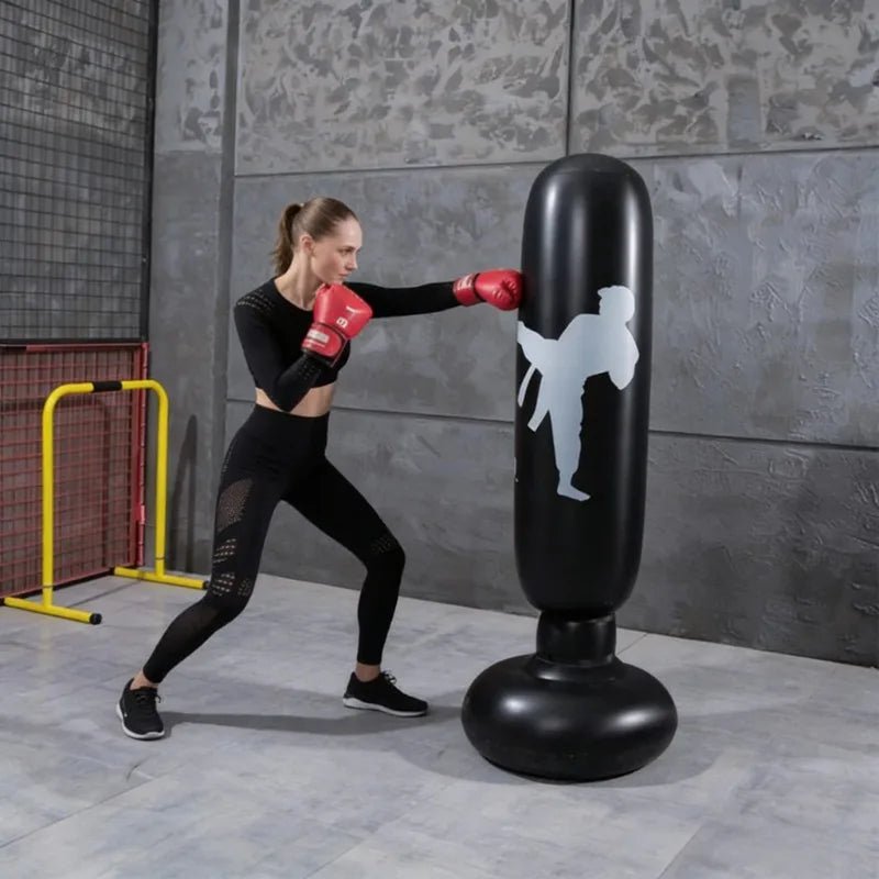 Woman practicing boxing on an inflatable punching bag in a gym setting.