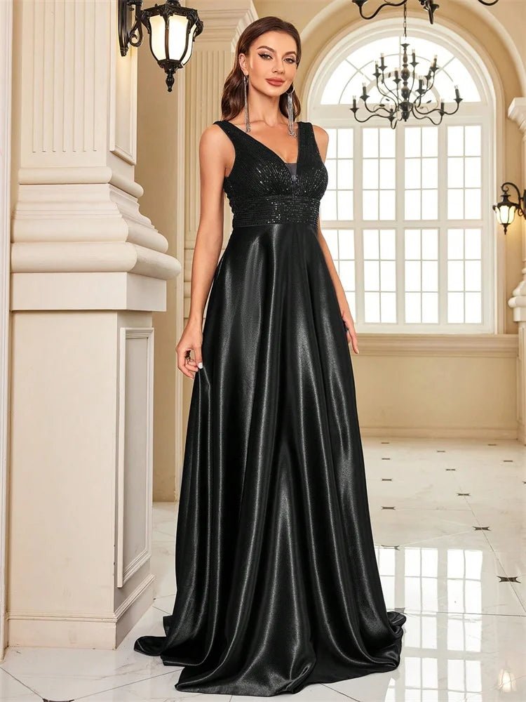 Woman in a black evening gown standing in an elegant interior setting.