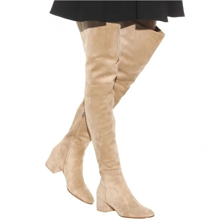 Beige knee-high boots worn with a black outfit on a white background