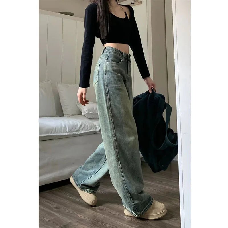 Person wearing light blue jeans and a black top in a room with a couch.