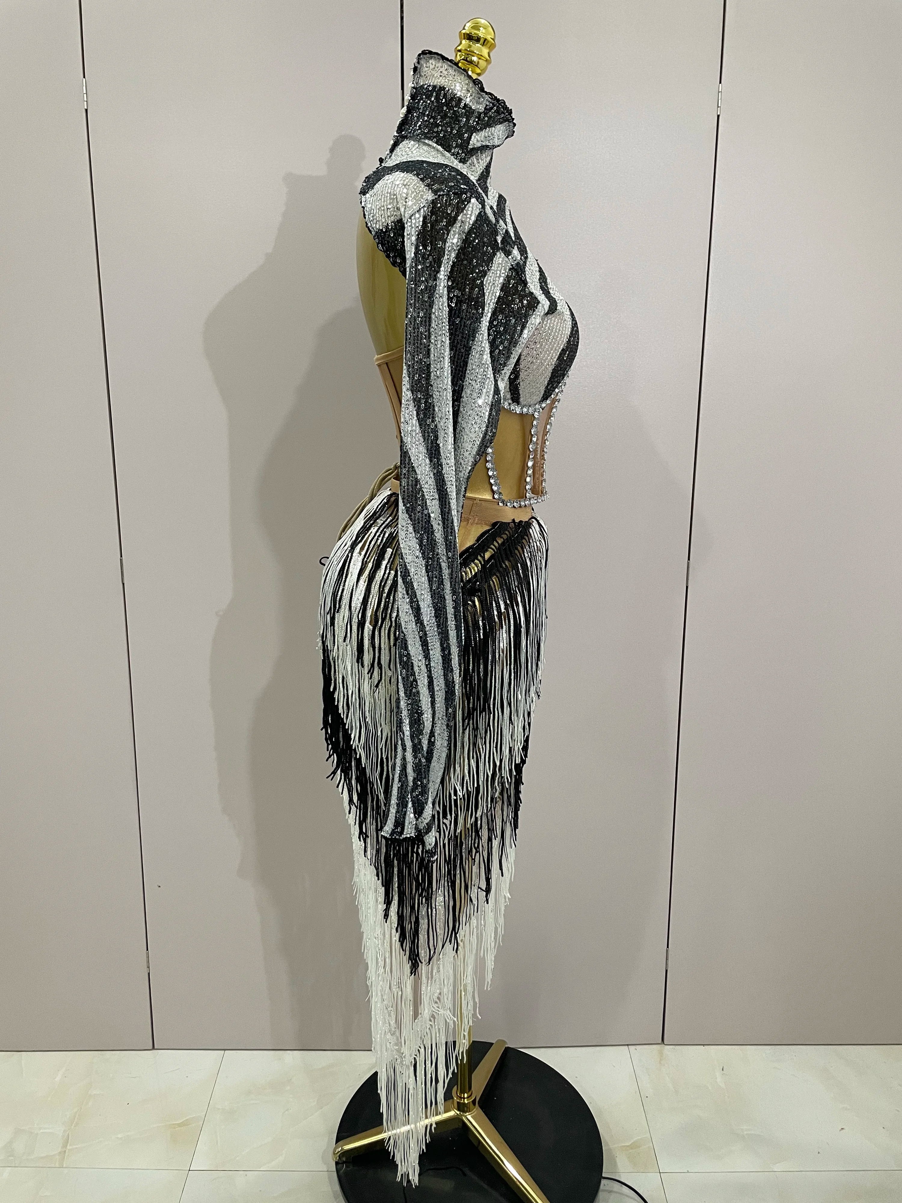 Mannequin wearing a zebra-striped dress with fringe details against a white wall.