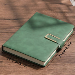 Green notebook with a gold buckle on a wooden surface, showing dimensions.