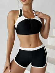 Woman wearing a black and white sports bra and shorts set on a plain background