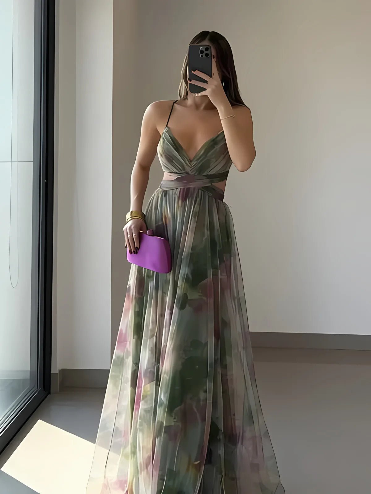 Woman in a floral dress holding a purple clutch in a minimal indoor setting.