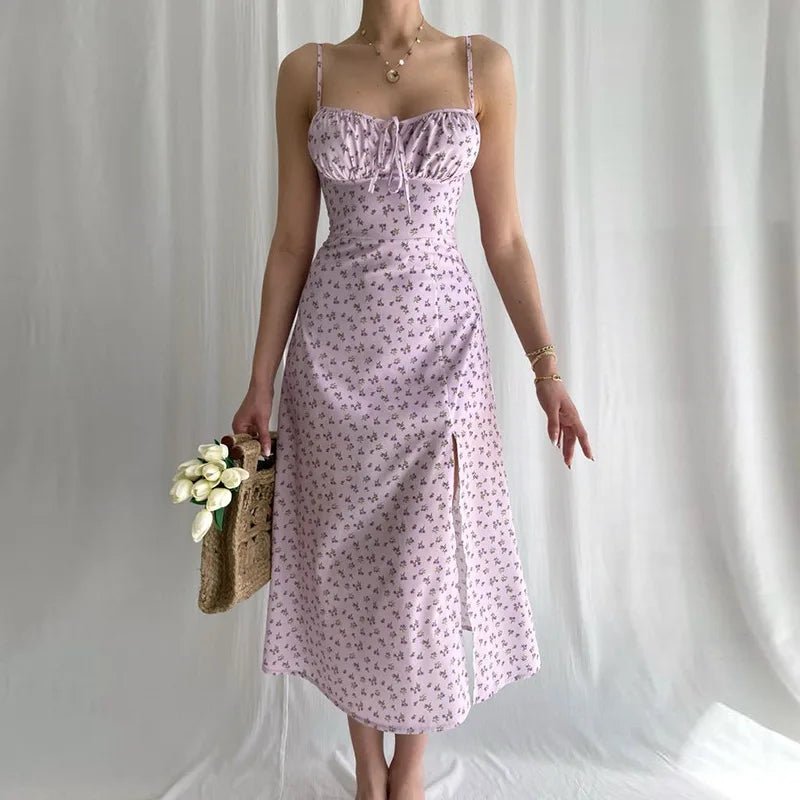 Woman wearing a pink floral dress holding a woven bag with flowers against a plain background