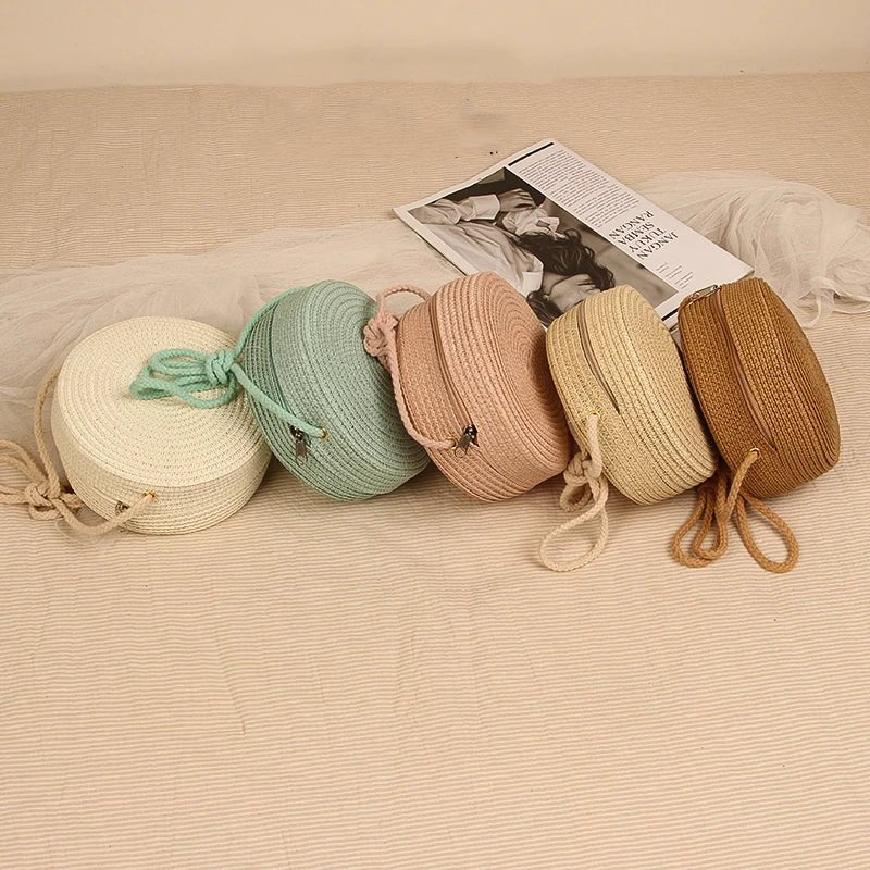 Five woven bags in different colors arranged on a textured surface with a magazine underneath.