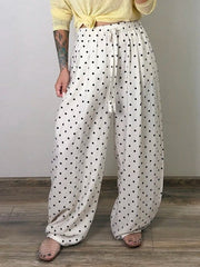 Person wearing white pants with black polka dots and a yellow top against a plain background