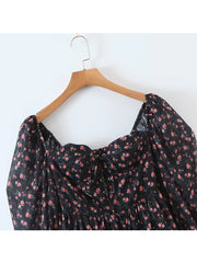 Black floral dress on a wooden hanger against a white background