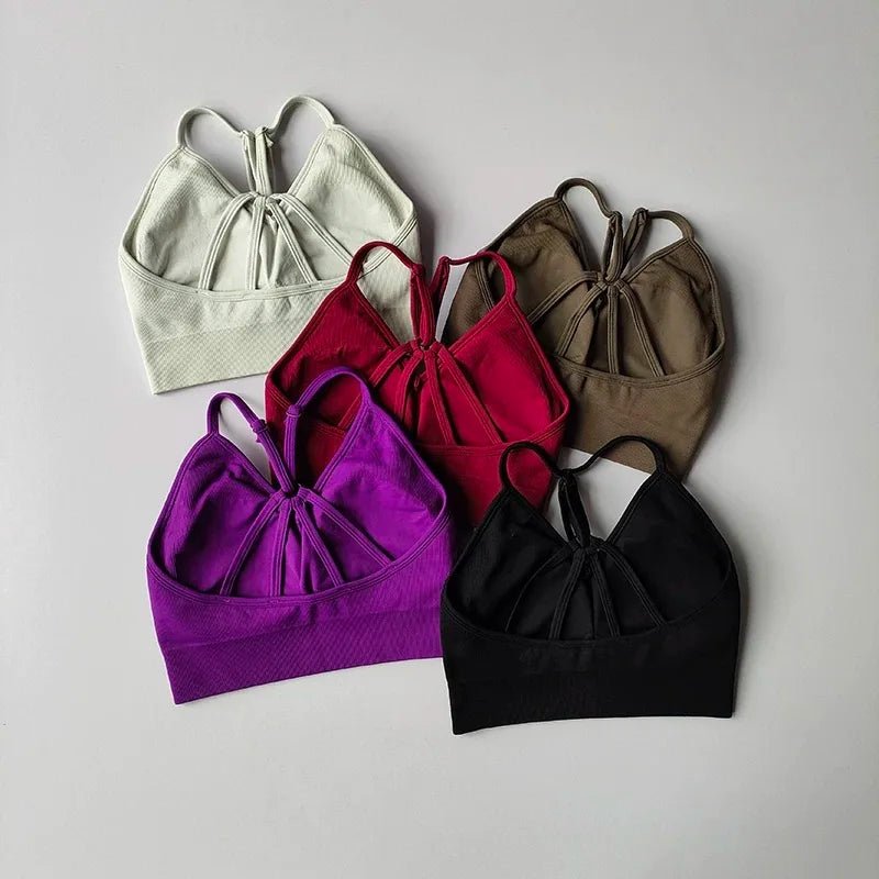 Five sports bras in different colors on a gray background