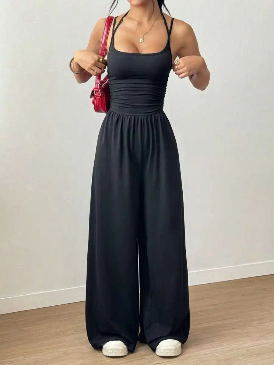 Person wearing a black jumpsuit with a plain background
